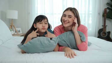 Mutlu Asyalı kız ve akıllı anne kameraya bakarken yatağa uzanıyorlar. Enerjik aile vakit geçirir ve birlikte yatmaya hazırlanır. Sevimli kız ve anne kameraya gülümsüyor sevgi ve şefkat gösteriyorlar. Pedagoji.