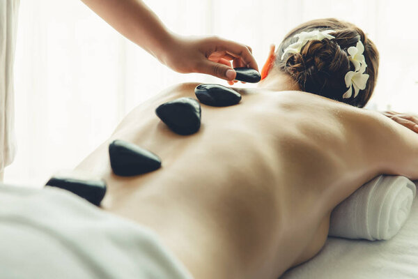 Массаж горячими камнями в спа-салоне на роскошном курорте с дневной легкой атмосферой спокойствия, блаженной клиенткой, наслаждающейся спа-массажем из базальтового камня, скользит по телу с успокаивающим теплом. Quiescent