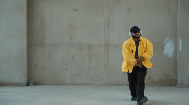 Hippi sokak, şehir merkezinde ayak izleri gösteriyor ya da pratik yapıyor. Hareketli genç break dansçı hareketi ve kol ve bacak esneme hareketi. Açık hava sporu 2024. Gri arka plan. Hip hop modası. Hiphop.