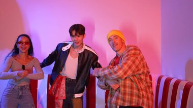 Hip hop müziğine yönelirken kameraya bakan beyaz dansçı. Profesyonel çeşitlilikteki dans ekibi stüdyoda pembe ışıkla enerjik hareketler ve çılgın adımlar sergiliyor. Mutluluk.