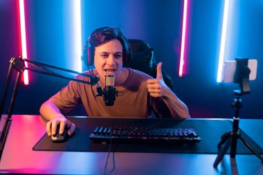 Oyun kanalı, online oyun oynayan akıllı flamalı oyun sunucusu, kulaklık takan, neon ışıklandırma odasındaki takım oyuncusuyla akıllı telefondan canlı yayında konuşan izleyiciler. Bireysel.