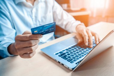 Genç adam, laptop bilgisayar başvurusu ya da web sitesinde online alışveriş yapmak için kredi kartı kullanıyor. E-ticaret ve online alışveriş konsepti. uds