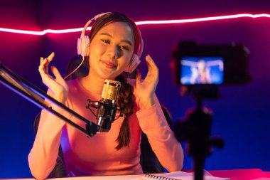 Yaratıcı yayın kanalı sosyal medyada pozitif podcasttaki dinleyicilerle birlikte müziği dinliyor, pastel renkli kulaklıklar takıyor, neon stüdyodaki kameraların mikrofon kayıtlarını kullanıyor. Taktik.