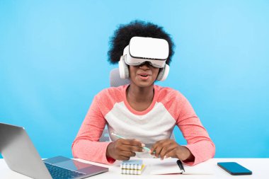 Genç Afro-Amerikalı VR kulaklıklı grup sınıfında sunum yapan dizüstü bilgisayar çalışma web sitesi kullanarak teknolojik yeniliklerin ve interaktif 3D tasarım gelecekçiliğinin mavi arkaplanını izole etti. Entrika.