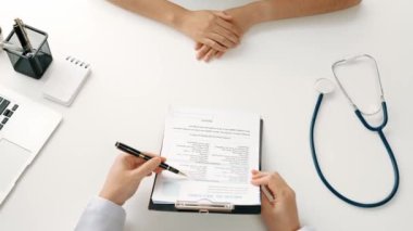 Klinikteki ya da hastane ofisindeki doktor randevusuna katılan hasta, tıbbi tedavi seçeneklerini tartışıyor ve muayene sonuçlarını ya da hastalıkla ilgili tıbbi kayıtları açıklıyor. Ağır çekim. Katı.