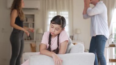 Sinirli ve mutsuz genç bir kız oturma odasında ebeveyninin tartışması yüzünden gerginliğin ortasında kanepede oturuyor. Sağlıksız ev hayatı ve travmatik çocukluk depresyona dönüşür.