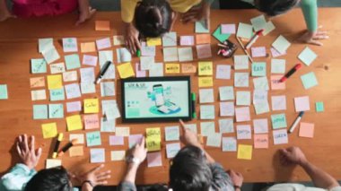 Ux Ui tasarımı kullanılarak dijital program ve yazıları tartışan ve gösteren geliştirici ekibin hava görüntüsü. İş dünyasına tepeden bakan insanlar telefon ve bilgisayar için kablo prototipi geliştiriyorlar. Sempozyum.