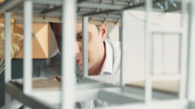 Kafkasyalı mimar mühendisinin yakın çekimi ev inşaatını denetlemek ve bina malzemelerini kontrol etmek. Proje yöneticisi modele dikkatlice bakarken kalemi işaret ediyor. Yönlendirici.