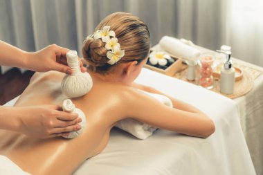 Sıcak bitkisel top spa masaj vücut tedavisi, masör kadın vücuduna nazikçe şifalı bitki torbası bastırıyor. Aromaterapi dinlenme sükuneti ve sükuneti kaplıca salonundaki atmosferi aydınlatıyor. Sessiz.