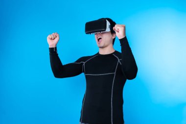 VR gözlük takan akıllı bir oyuncu, sanal dünyada sanal dünyada sanal gerçeklikle dijital fütüristik teknolojiyi birbirine bağlayan izole edilmiş mavi arka plan ekranını kaldırıyor. Entrika.