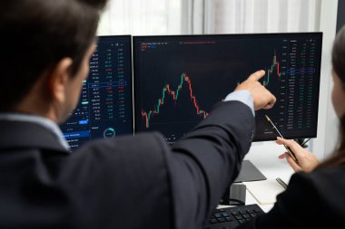 Dinamik borsada döviz kuru yatırımını tartışan iki ticaret simsarı iki bilgisayar ekranında gerçek zamanlı risk grafiği ya da modern ofisteki kar noktasını karşılaştırıyor. Varsayım.