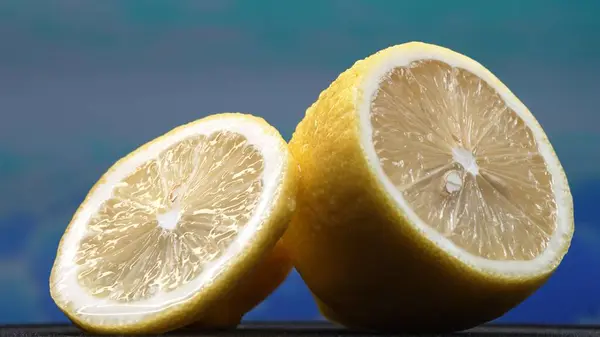 stock image A slice of lemon, bright yellow and vibrantly citric, lies exposed. The yellow flesh, with refreshing juice, reveals its segmented interior. The essence of citrus vibrancy. Slow motion. Comestible.