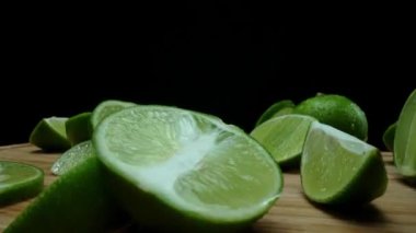 Yakın plan, canlı bir dilim taze kireç kırsal bir ahşap kesme tahtasının üzerinde duruyor. Tazelik ve canlılık yayıyor. Kesme tahtasına konmuş yeşil limon diliminin yarı saydam zarları. Geliştirilebilir.