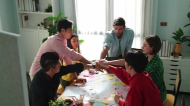 Mutlu yaratıcı takımın zihin haritası çizerken el ele tutuşması. Çeşitli insanlar birlikte çalışarak pazarlama fikri üzerinde çalışıyor ve yapışkan notlar kullanarak planlarını paylaşıyorlar. Cemaat