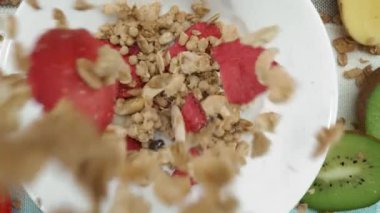 Sağlıklı bir mısır gevreği ve kuru çilek tabağına yakın durun. Yukardan aşağıya mısır gevrekli kase, mavi ve beyaz peçeteli kuru meyve. Makrografi. Ağır çekim. Kahvaltıda. Pabulum.