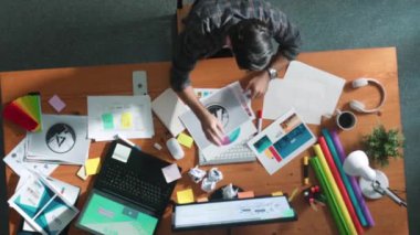 Toplantıda tasarımcı yazma ve logo grafiği tasarlamanın en üst görünümü. Renkli paletler üzerinde çalışan iş adamlarının yakınlaşması ve masaya kağıt ve ekipman ile yapışkan notlar yazmak. Sempozyum.