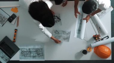 Akıllı mimar mühendis belgelerini güvenlik kaskı ve planıyla toplantı masasına yerleştirdi. Birlikte çalışan ve bina inşaatı tasarlayan iş adamlarının hava görüntüsü. Hizalama.