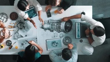 Türbin motoru tasarlamak için çalışan akıllı mühendis takımının yukarıdan aşağıya hava görüntüsü. Profesyonel teknisyen jet motoru yapımını tartışırken motorun bir kısmını işaret ediyor. Hizalama.