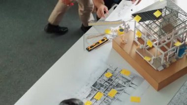 Profesyonel mimar mühendis ekibinin en iyi görüntüsü ev modelini incelerken, yöneticinin elinde bina inşaatı hakkında sorular sorması. Çeşitli mühendislerden oluşan bir grup birlikte çalışıyor. Hizalama.