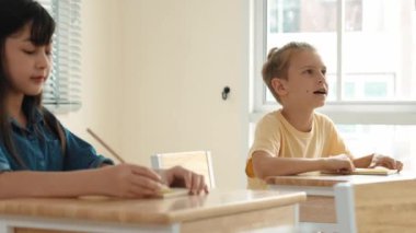 Zeki öğrenci sınıfta otururken öğretmenlerin sorularına cevap verir. Tahtaya bakarak ve ilköğretim sınıfına katılarak çeşitli çocuklar öğreniyor ve öğreniyor. Eğitim konsepti. Pedagoji.
