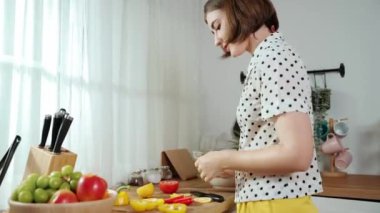 Kafkaseli anne kahvaltıda sebze pişirirken mutlu anne de modern mutfakta salata için taze malzemeler hazırlıyor. Hizmetçi sağlıklı yemek pişiriyor. Dikkat konsepti. Pedagoji.