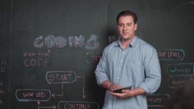 Kodlama programıyla ilgili öğrenci sorusuna beyaz öğretmen cevap veriyor. Beyaz kız, STEM teknoloji sınıfında dizüstü bilgisayar ekranı görüntülerken soru sormak, oy vermek, gönüllü olmak için elini kaldırdı. Öğretim