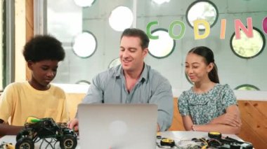 Yakışıklı öğretmen, sofrasında araba modeli ve panosu olan bir dizüstü bilgisayar kullanarak elektronik ekipmanı açıklıyor. Çok kültürlü çocuklar BTMM sınıfında araba modeli yapısını anlatırken öğretmenlerini dinlerler. Öğretim