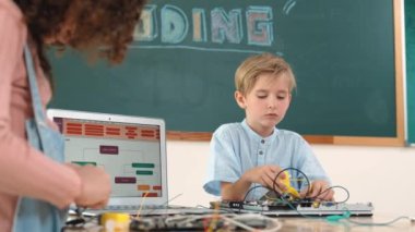 Kafkas akıllı çocuk kök teknoloji dersinde tornavida kullanarak ana tahtayı tamir ederken aynı zamanda gülümseyen öğrenci de dizüstü bilgisayar ekranı kodlu elektronik makineyi incelemek için birlikte çalışıyor. Pedagoji.