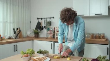 Mutlu baba yemek pişirirken müziğe geçiyor ve modern mutfakta öğle yemeği hazırlıyor. Aktif baba, sebze ve mutfak gereçleri ile çevrili sağlıklı yemek ya da salata yaparken şarkıyla dans ediyor. Pedagoji.