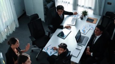 Akıllı yönetici finansal grafiğinin üst görüntüsünden çeşitli takımlara geçerken, bir grup çok kültürlü iş adamı toplantıda hisse yatırım grafiği kullanarak pazarlama stratejisi planlıyorlar. Müdürlük.