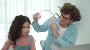 Beyaz bir baba kızına kulaklık takarken kız da kod öğreniyordu. Babam, mühendislik öğretirken liseli kızla ilgilenir ve dizüstü bilgisayar kullanarak Ai üretir. Çevrimiçi öğrenme. Pedagoji.