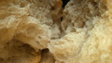 Koyu arkaplanda taze ekmek parçacıkları var. Tahta tepsiye yerleştirilmiş ekmeğin makro fotoğrafçılığı. Kamera hareketini yakınlaştır. Gurme ve fırın konsepti. Poster için tasarım, yemek blogu. Pabulum.