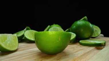 Yakın plan, canlı bir dilim taze kireç kırsal bir ahşap kesme tahtasının üzerinde duruyor. Tazelik ve canlılık yayıyor. Kesme tahtasına konmuş yeşil limon diliminin yarı saydam zarları. Geliştirilebilir.