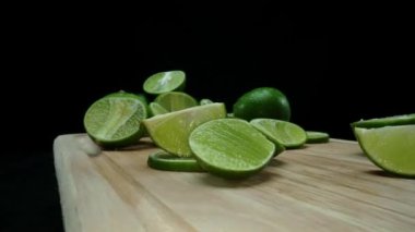 Yakın plan, canlı bir dilim taze kireç kırsal bir ahşap kesme tahtasının üzerinde duruyor. Tazelik ve canlılık yayıyor. Kesme tahtasına konmuş yeşil limon diliminin yarı saydam zarları. Geliştirilebilir.