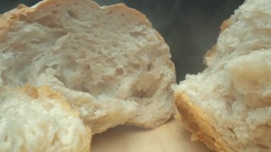 Koyu arkaplanda taze ekmek parçacıkları var. Tahta tepsiye yerleştirilmiş ekmeğin makro fotoğrafçılığı. Kamera hareketini yakınlaştır. Gurme ve fırın konsepti. Poster için tasarım, yemek blogu. Pabulum.