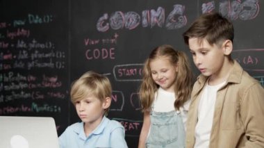 Çocuğun dizüstü bilgisayar mühendisliği kodunu ve yazım programını kullanırken bir grup zeki öğrencinin etrafı STEM teknoloji sınıfında arkadaşlarıyla çevriliyken karatahtaya oturması. Etkinlik.