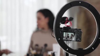 Arka plan kamera görüntüsü, iki kadın nüfuzlu kişinin canlı yayın yapan video görüntülerini kaydediyor. Makyaj, sosyal medya ya da blog. Çevrimiçi pazarlama yayını için kozmetik ürünleri olan genç bir kız.