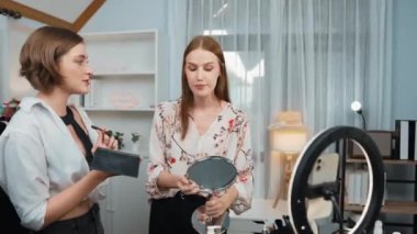 Etkilenen iki ortak canlı yayında video görüntülerini çekiyor makyaj malzemesi prim sosyal medya veya blog. Kozmetik stüdyosu ışıklandırmalı mutlu genç kız çevrimiçi pazarlama oturumu yayını için..