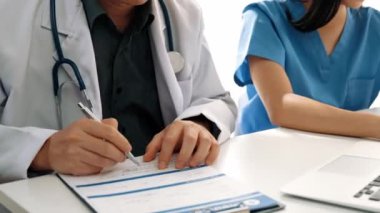 Hastane masasında birlikte çalışan ve tıbbi tedavi planlayan çeşitli profesyonel sağlık görevlileri. Takım çalışması başarılı hastalıklara ve hastalıklara yol açar. Ağır çekim. Katı.