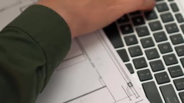 Mimari ya da mühendis, modern ofiste doğruluk için mimari belgeye veriler yazıp, dizüstü bilgisayarda ayrıntılı tasarım planı olan bir yapı tasarlıyor. - Yakın çekim. Tanımlama.