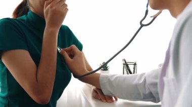 Hasta klinikte ya da hastane ofisinde doktor randevusuna gidiyor. Hastaların risk faktörünü tespit etmek için nabzını ölçmek için steteskopla doktor muayenesi ve teşhis semptomları. Ağır çekim. Katı.