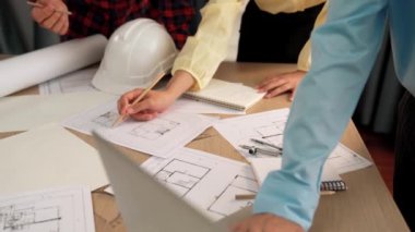 Mimarlık ve güvenlik mühendisi, modern ofiste dizüstü bilgisayarda mimari belge ve ahşap blokla sergilenen planlar hakkında tartıştı. - Yakın çekim. Tanımlama.