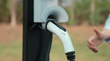Otomobil seyahati sırasında elektrikli araba için şarj olan kadın Autumanl sezonunda doğal orman ya da milli parkta. Tatil ve tatil boyunca çevre dostu seyahat. Yükselt