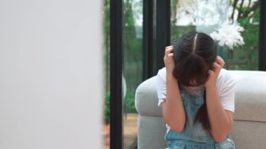 Stresli ve mutsuz genç kız köşeye kıvrılıp kulaklarını kapatarak arka planda ebeveyninin tartışmasını engelliyor. Evde aile içi şiddet ve travmatik çocukluk depresyona dönüşür. Titiz