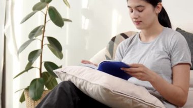 Kanepede oturan bir kadın ders kitabı okuyarak sosyal ve mesleki teknoloji bilgisini artırır ya da akıllı bir anne olmak için çocuk yetiştirir. Hayat boyu öğrenme konsepti. Uyumsuzluk.