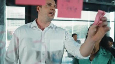 Yetenekli işadamı, cam duvara renkli yapışkan notlar yapıştırarak proje yöneticisine pazarlama fikrini sundu. Proje yöneticisi yatırımcıya projeyi gösteriyor, anlatıyor, gösteriyor. Yönlendirici.