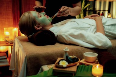 Kaplıca salonunun sakin atmosferi, kadın müşteri sıcak mum ve lüks yüz kremi masajıyla kendini yenileme zevkine kapılıyor. Yüz bakımı ve güzellik konsepti. Sessiz.