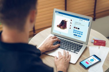 Genç adam internet bankacılığı için kredi kartlı dizüstü bilgisayar kullanıyor. İnternet üzerinden alışveriş yapıyor. Banka kartıyla modern ve kullanışlı online satın alma. Açılıyor