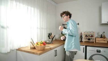 Mutlu baba yemek pişirirken müziğe geçiyor ve modern mutfakta öğle yemeği hazırlıyor. Aktif baba, sebze ve mutfak gereçleri ile çevrili sağlıklı yemek ya da salata yaparken şarkıyla dans ediyor. Pedagoji.