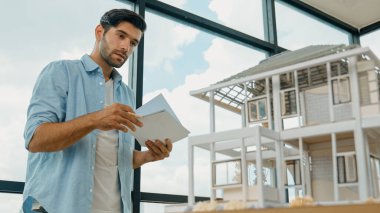 Tasarımlı ev modelini karşılaştıran profesyonel mimar mühendisi. İşadamı gayrimenkul projesine yatırım yapmaya karar verdi. Proje yöneticisi planla karşılaştırarak evi kontrol ediyor. İzleme